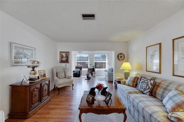 living room with a textured ceiling and light wood-type flooring