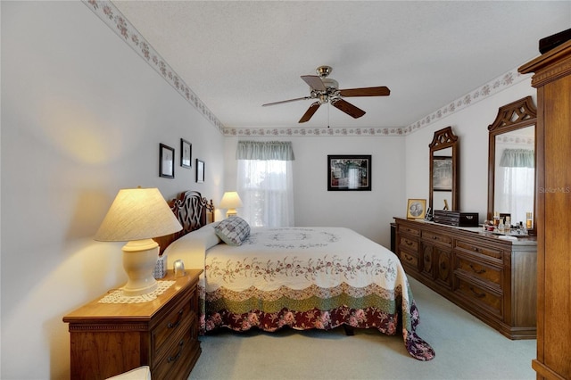 bedroom featuring a textured ceiling, light colored carpet, and ceiling fan