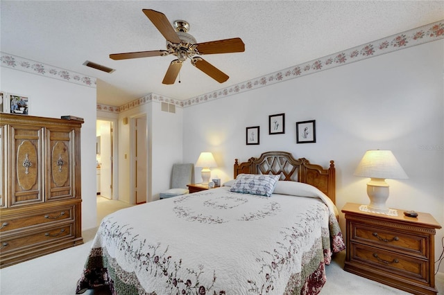 bedroom with ceiling fan, light carpet, and a textured ceiling