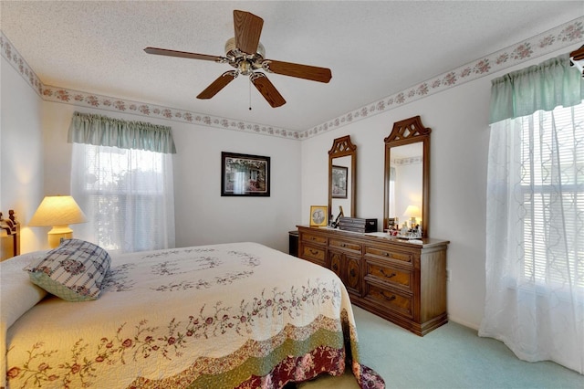 bedroom with ceiling fan, light carpet, and a textured ceiling