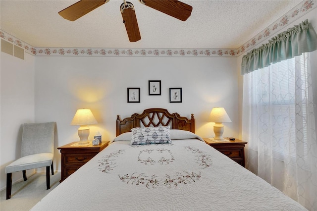 carpeted bedroom featuring ceiling fan and a textured ceiling