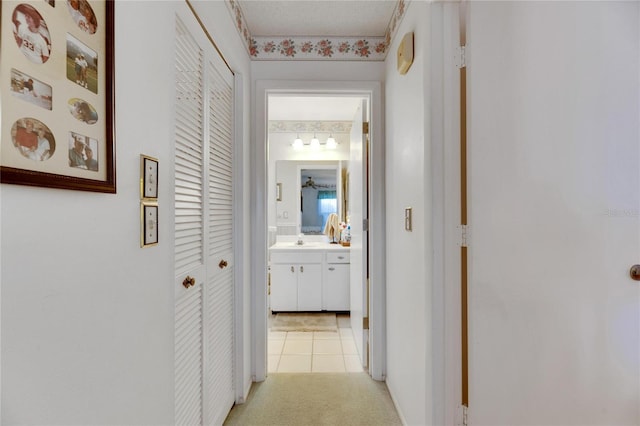 corridor featuring sink and light colored carpet