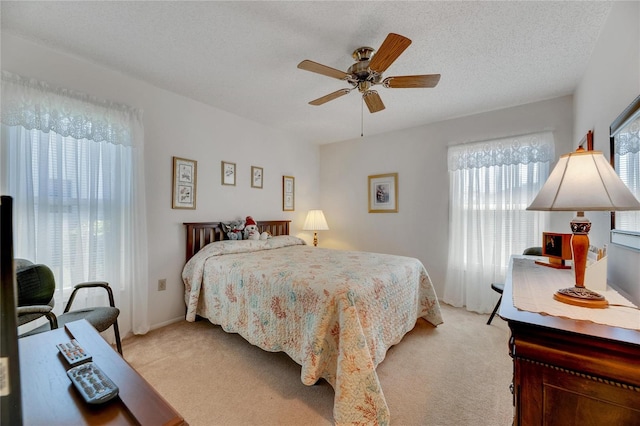 carpeted bedroom with ceiling fan, a textured ceiling, and multiple windows