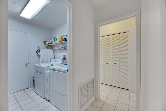 washroom with washer and clothes dryer, a textured ceiling, and light tile patterned flooring