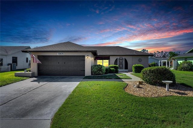 single story home featuring a garage, central air condition unit, and a lawn