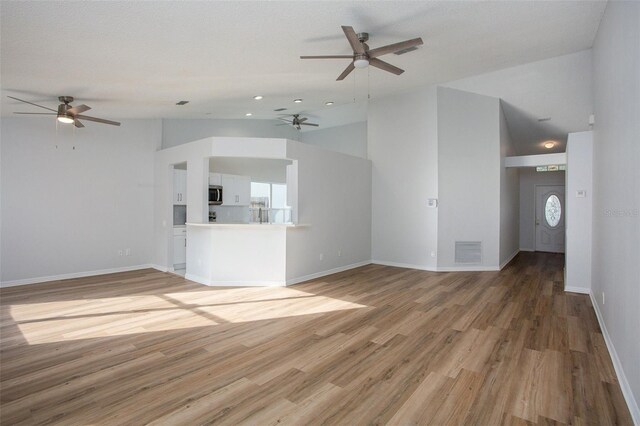 unfurnished living room with a textured ceiling, hardwood / wood-style flooring, high vaulted ceiling, and ceiling fan