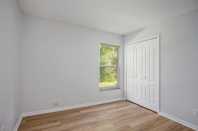 unfurnished bedroom with a closet, a textured ceiling, and light wood-type flooring