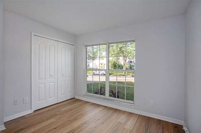 unfurnished bedroom featuring light hardwood / wood-style flooring, a textured ceiling, and a closet