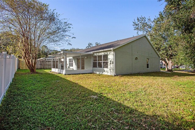 rear view of property with a sunroom and a lawn