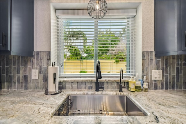 kitchen with decorative backsplash, sink, and light stone counters