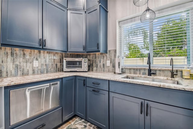 kitchen with backsplash, light stone countertops, and sink