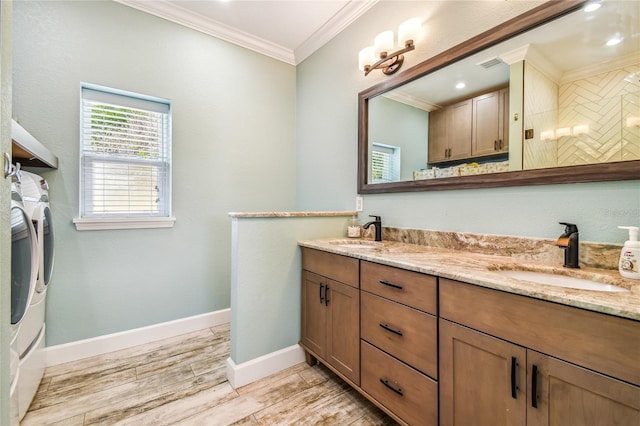 bathroom featuring hardwood / wood-style floors, a tile shower, washing machine and clothes dryer, ornamental molding, and vanity