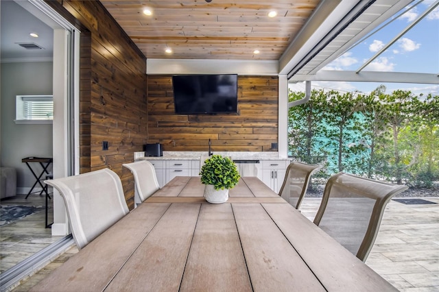 dining space with wood ceiling and wood walls