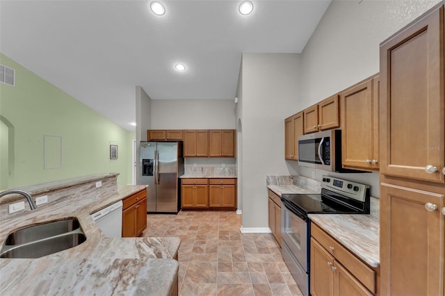 kitchen with sink, light stone counters, stainless steel appliances, and high vaulted ceiling