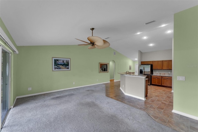 kitchen featuring a center island, vaulted ceiling, stainless steel fridge with ice dispenser, light colored carpet, and ceiling fan