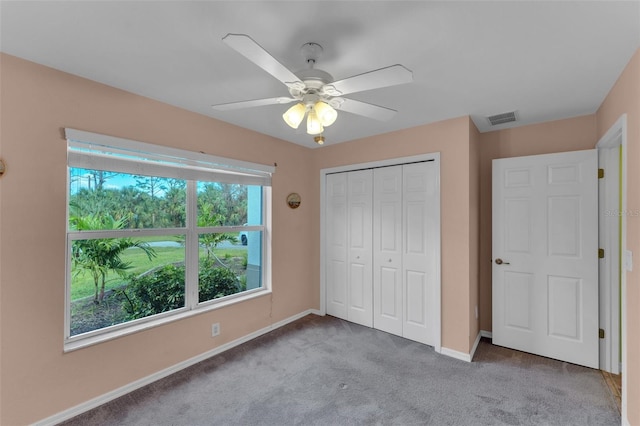 unfurnished bedroom featuring light colored carpet, multiple windows, a closet, and ceiling fan