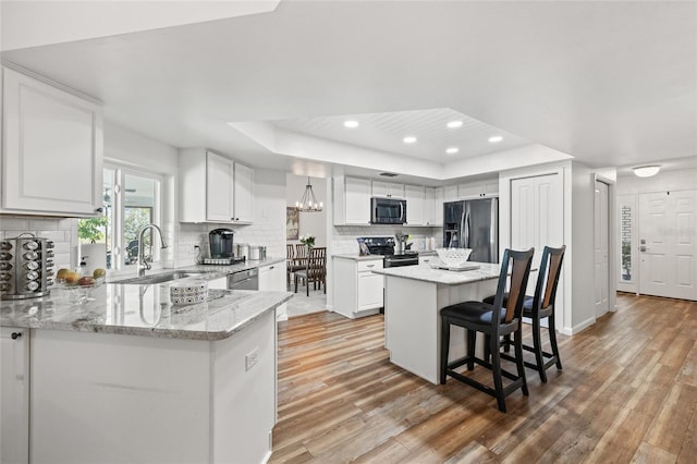 kitchen featuring sink, a breakfast bar area, appliances with stainless steel finishes, a tray ceiling, and white cabinets