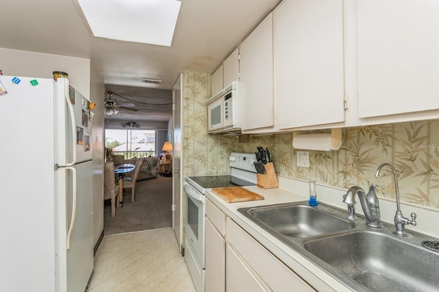 kitchen with sink, white cabinets, white appliances, and a skylight