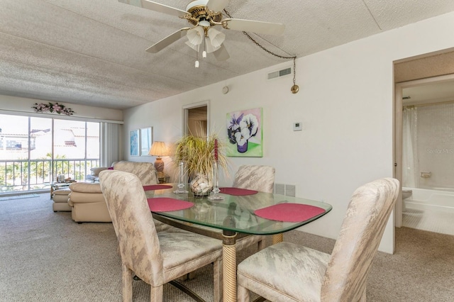 carpeted dining room with a textured ceiling and ceiling fan