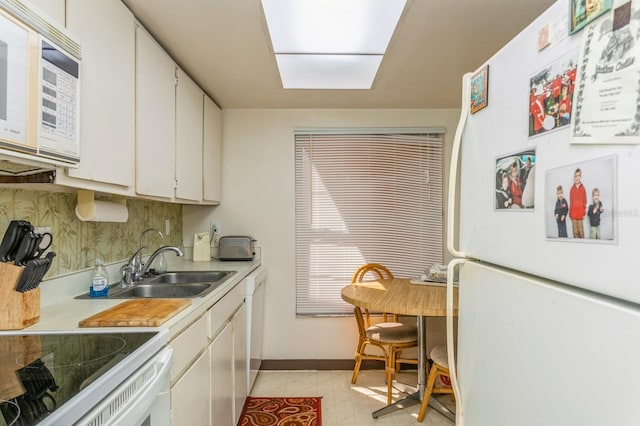 kitchen with sink, white cabinetry, and white appliances