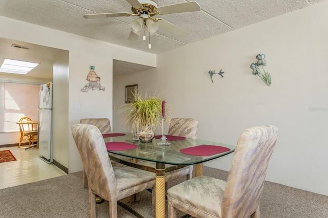 dining space featuring ceiling fan, a textured ceiling, and light colored carpet