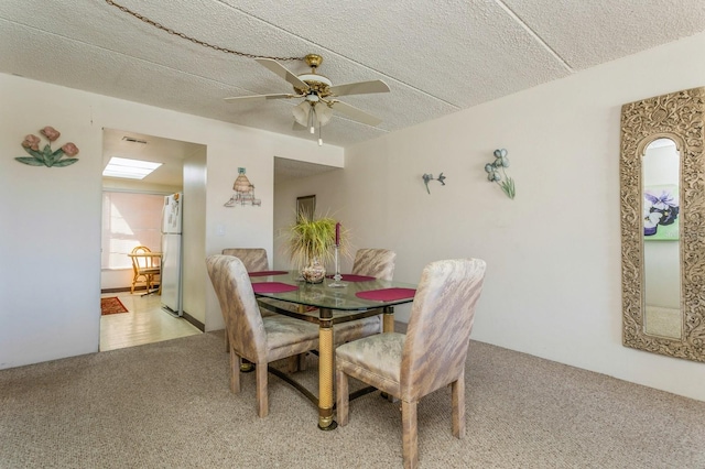 dining area with ceiling fan, a textured ceiling, and light colored carpet