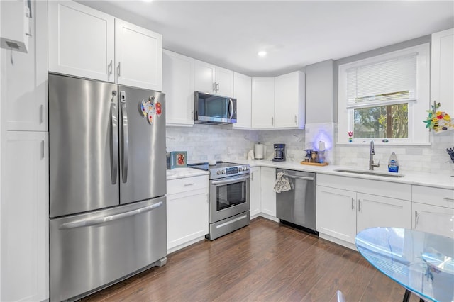 kitchen with decorative backsplash, appliances with stainless steel finishes, white cabinetry, dark wood-type flooring, and sink