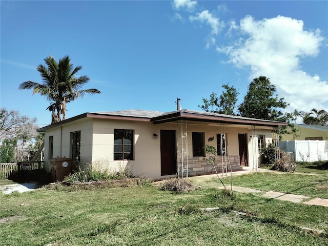 view of front of home featuring a front lawn, a porch, fence, and stucco siding