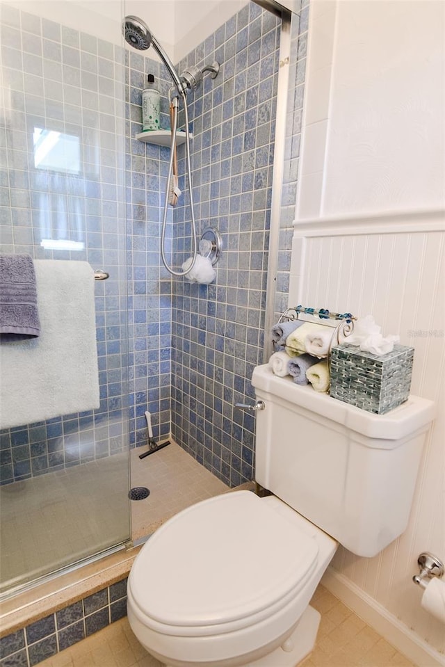 bathroom featuring tile patterned floors, a shower with shower door, and toilet