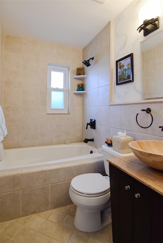 full bathroom with toilet, tile walls, tile patterned floors, vanity, and tiled shower / bath combo