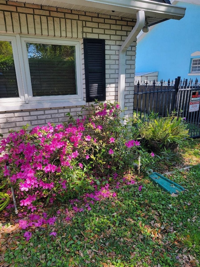 exterior details featuring brick siding and fence
