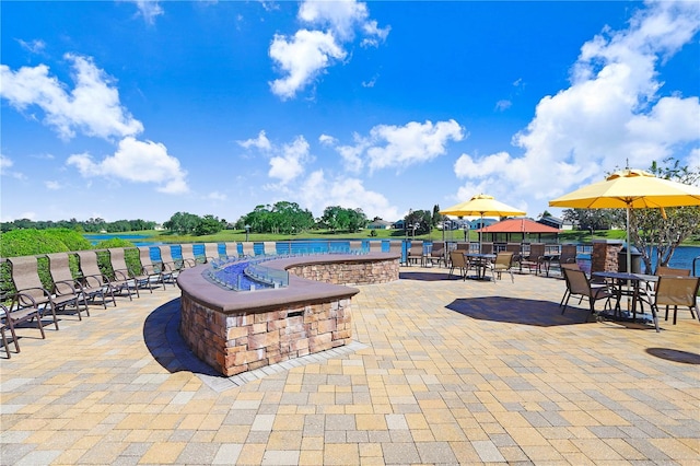 view of swimming pool featuring a water view and a patio area