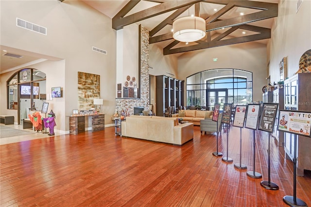 living room with hardwood / wood-style floors, beam ceiling, and high vaulted ceiling