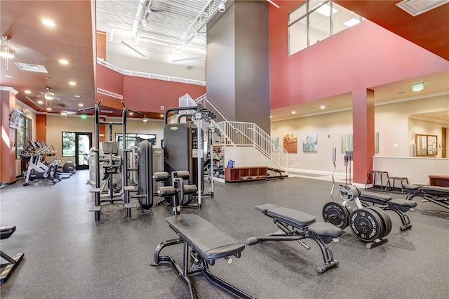 exercise room with ceiling fan and a towering ceiling