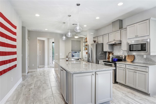 kitchen featuring appliances with stainless steel finishes, a center island with sink, pendant lighting, and gray cabinetry