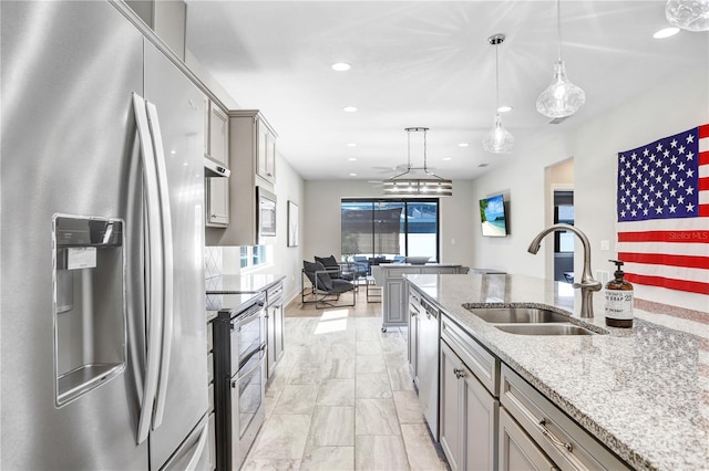 kitchen with stainless steel appliances, sink, pendant lighting, gray cabinets, and light stone counters