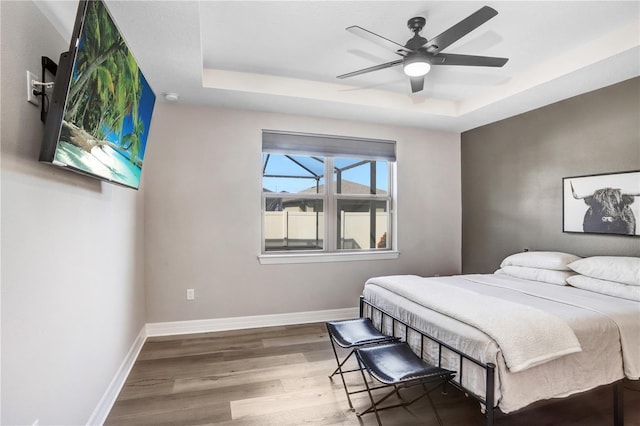 bedroom with ceiling fan, hardwood / wood-style flooring, and a tray ceiling