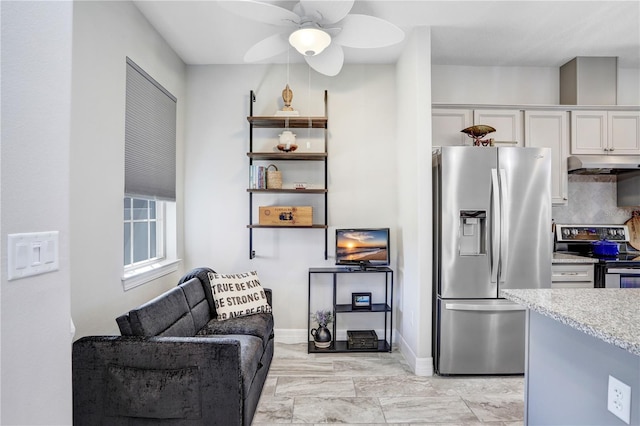 kitchen featuring stainless steel appliances, light stone countertops, ceiling fan, white cabinets, and tasteful backsplash