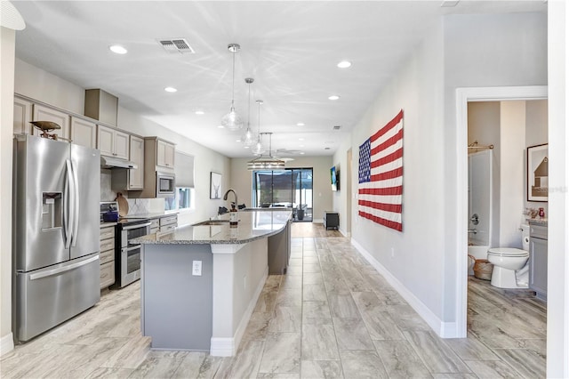 kitchen featuring hanging light fixtures, a center island with sink, sink, gray cabinets, and stainless steel appliances