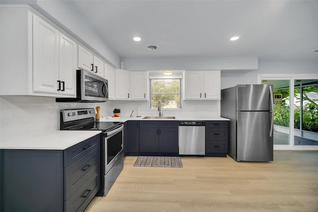 kitchen featuring sink, white cabinetry, stainless steel appliances, and light wood-type flooring