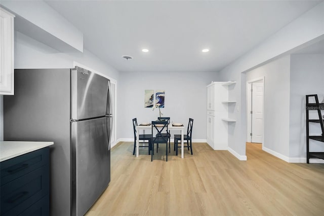 kitchen featuring white cabinetry, stainless steel refrigerator, and light hardwood / wood-style flooring