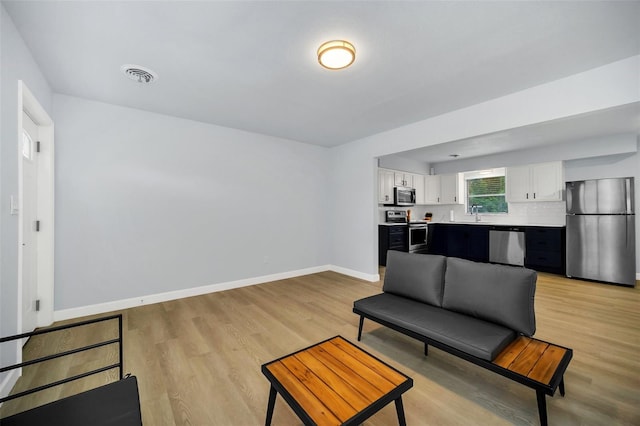 living room featuring sink and light hardwood / wood-style flooring