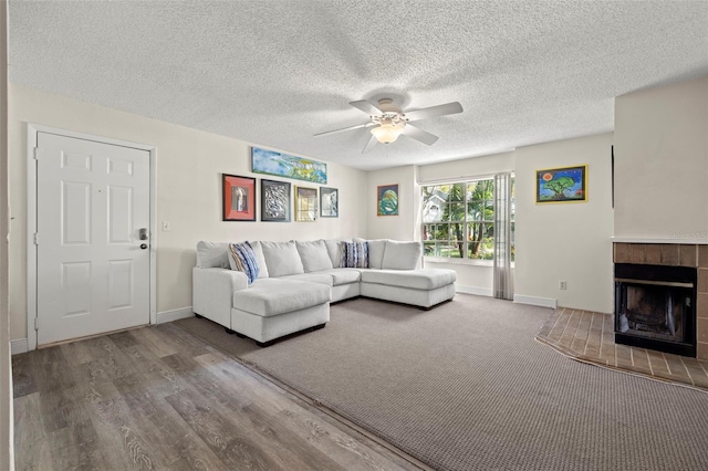 living room featuring hardwood / wood-style floors, a textured ceiling, a fireplace, and ceiling fan