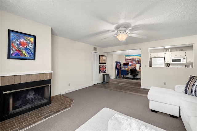 2101 Fox Chase Blvd Unit 106, Palm Harbor, FL 34683 - carpeted living area featuring ceiling fan, a brick fireplace, baseboards, and a textured ceiling