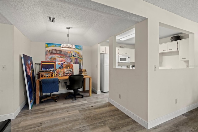 home office with hardwood / wood-style floors and a textured ceiling