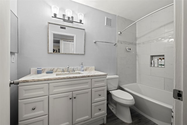 full bathroom featuring vanity, hardwood / wood-style floors, tiled shower / bath combo, and toilet