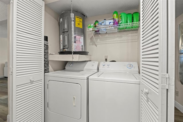 clothes washing area with washing machine and dryer, electric water heater, wood-type flooring, and a textured ceiling