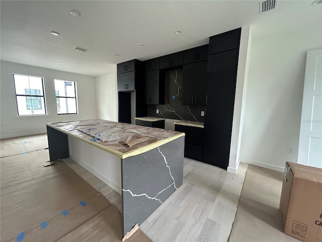 kitchen featuring a kitchen island, light hardwood / wood-style floors, and tasteful backsplash