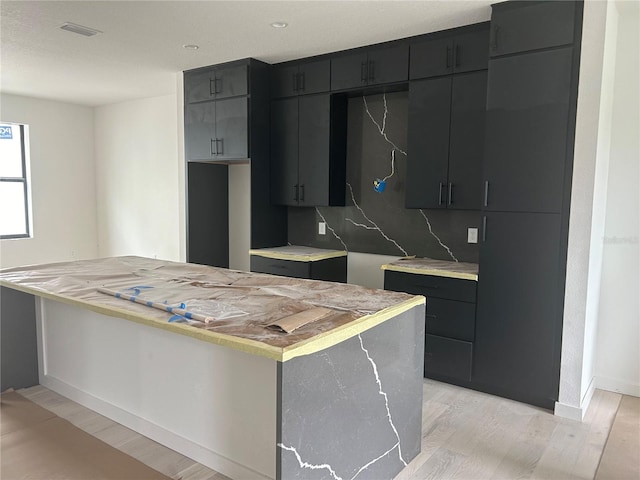 kitchen with tasteful backsplash, a kitchen island, and light hardwood / wood-style floors