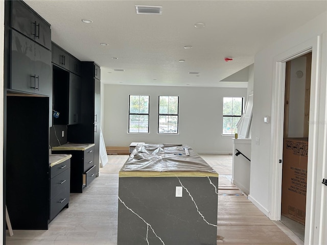 kitchen with a center island, a healthy amount of sunlight, and light hardwood / wood-style flooring